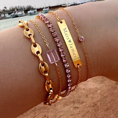 Goldene Armbänder-Set mit rosa Kristallen und Namensgravur auf Arm, modischer Schmuck.