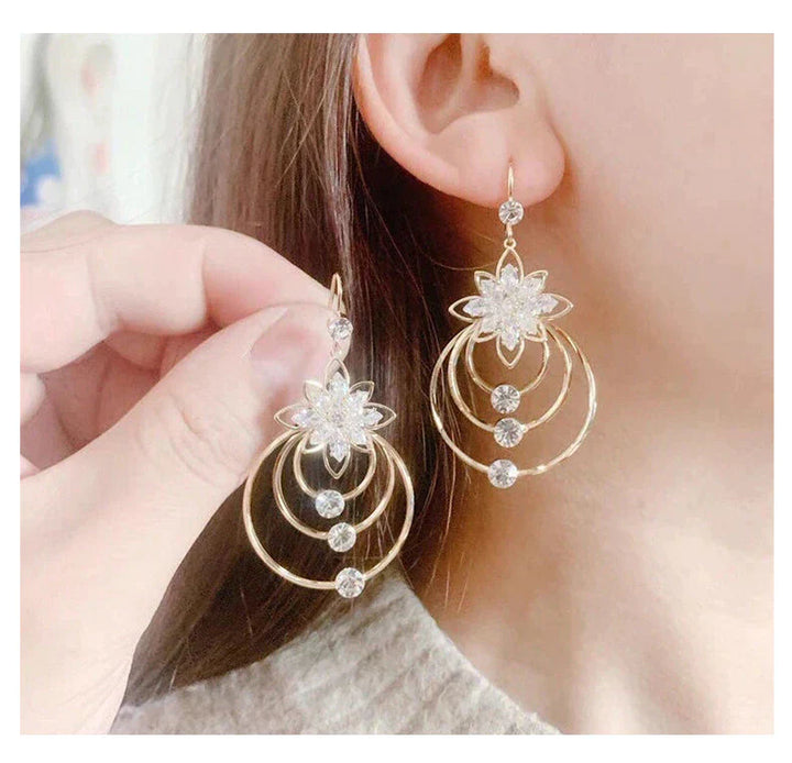 Goldene Ohrringe mit Blumenmotiv und Kristallen, eleganter Schmuck für Damen.