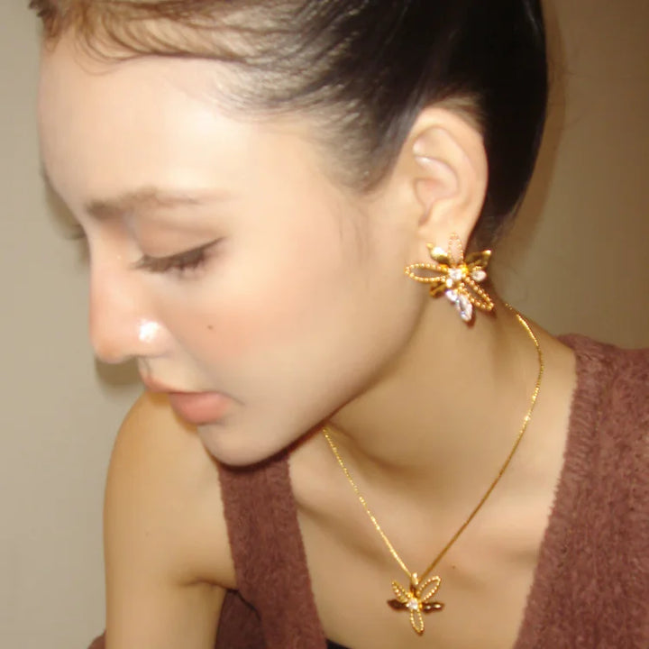 Frau mit goldener Halskette und Ohrringen in Blumenform, eleganter Schmuck, Nahaufnahme.