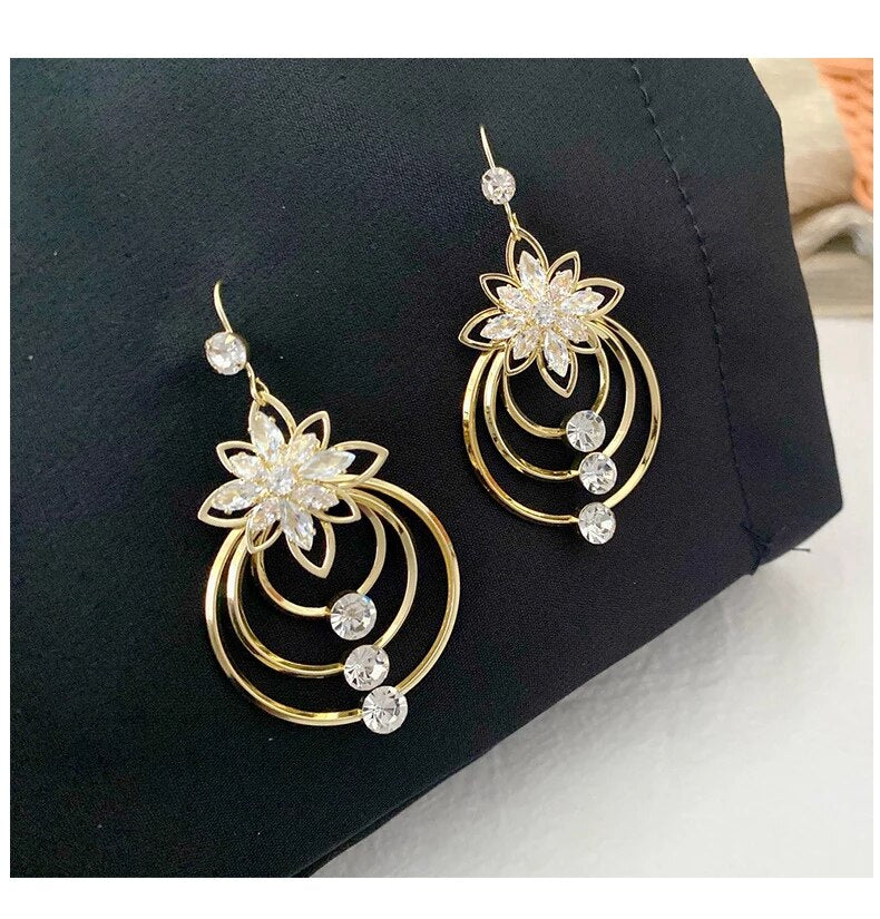 Goldene Ohrringe mit Blumenmotiv und Kristallen, eleganter Schmuck, Damenaccessoire.