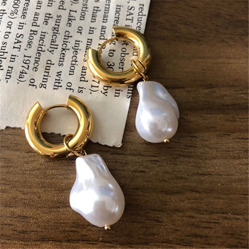Goldene Creolen mit weißen Barockperlen, eleganter Schmuck, modische Ohrringe, Damenaccessoire.