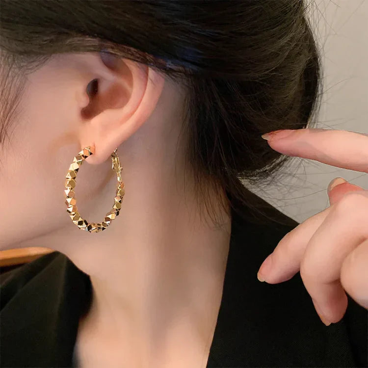 Goldene Creolen Ohrringe, geometrisches Design, modisch, Damen Schmuck, Nahaufnahme.