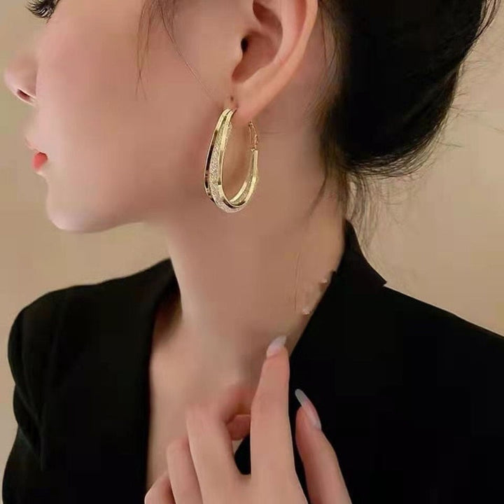 Frau mit großen goldenen Creolen-Ohrringen, elegantes Schmuckdesign, Nahaufnahme.