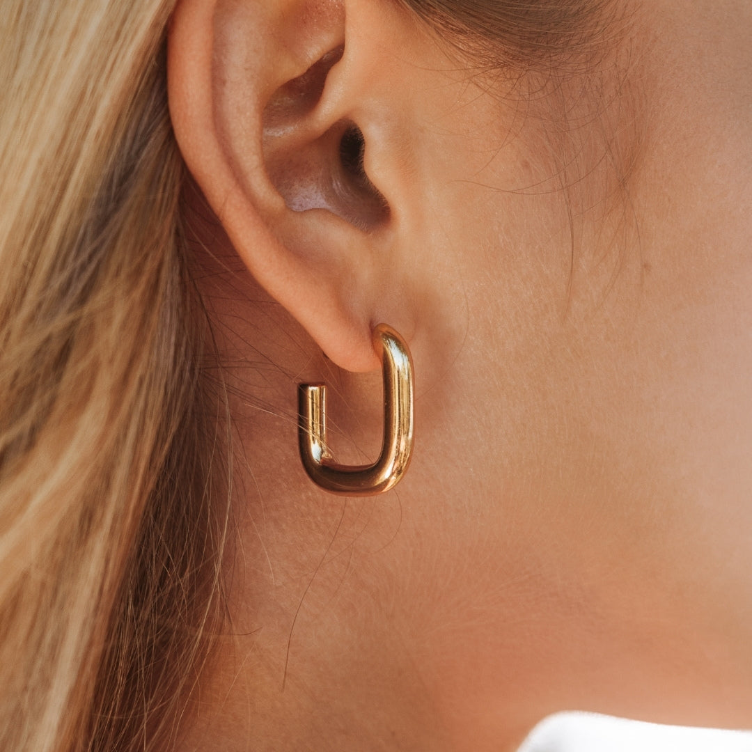 Goldene Creolen-Ohrringe, glänzend, modern, an Ohr getragen, Schmuck für Damen.