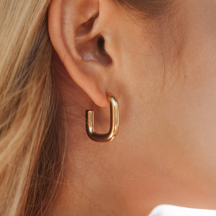Goldene Creolen-Ohrringe, glänzend, modern, an Ohr getragen, Schmuck für Damen.