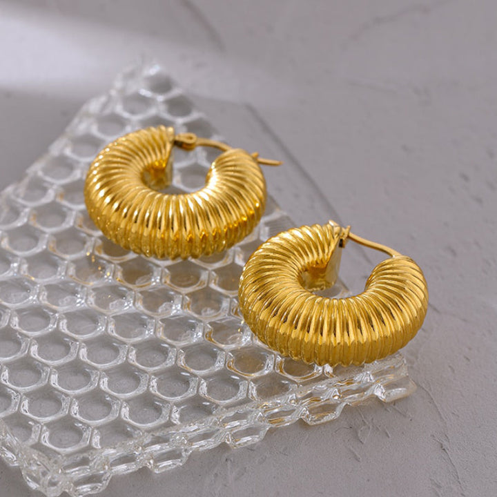 Goldene Creolen Ohrringe auf Glas, geriffelt, modisch, Schmuck, Damenaccessoire.