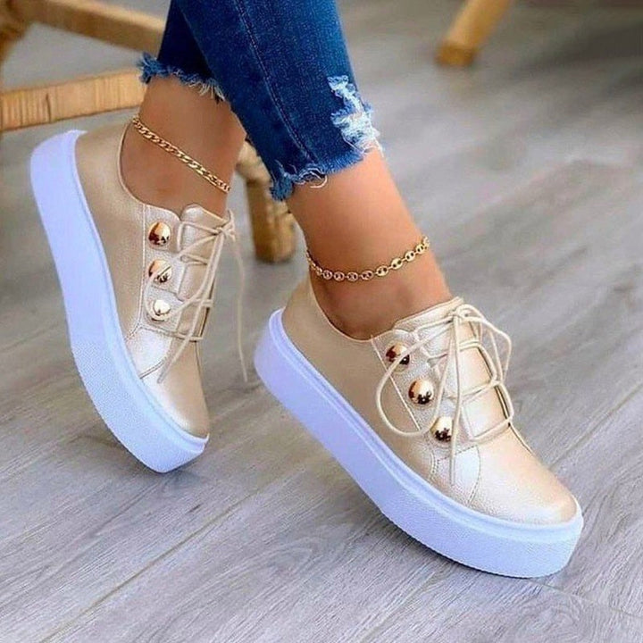 Goldene Damen-Sneaker mit Plateau, Schnürsenkeln und Jeans, modische Freizeitschuhe.