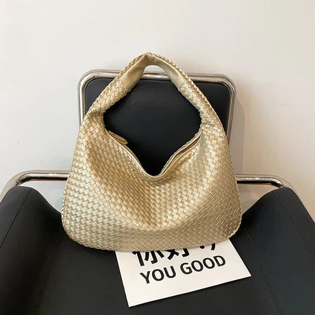 Goldene geflochtene Handtasche auf schwarzem Stuhl, modisches Accessoire, Damenmode.