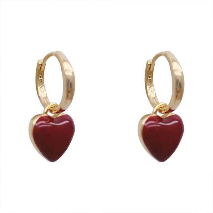 Goldene Ohrringe mit roten Herzanhängern, modischer Schmuck, elegantes Design.