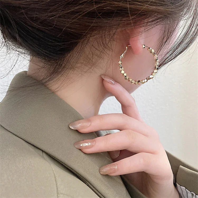 Frau mit goldenen Creolen-Ohrringen, eleganter Schmuck, modisches Accessoire, Nahaufnahme.