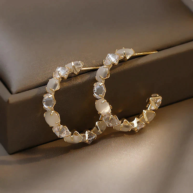 Goldene Creolen mit weißen und klaren Kristallen, eleganter Schmuck, modische Ohrringe.