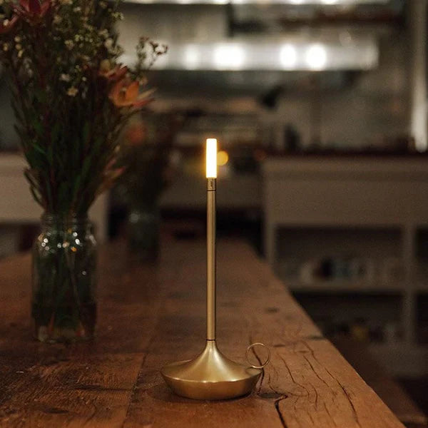 Goldene LED-Kerze auf Holztisch, moderne Beleuchtung, stilvolle Dekoration, gemütliches Ambiente.