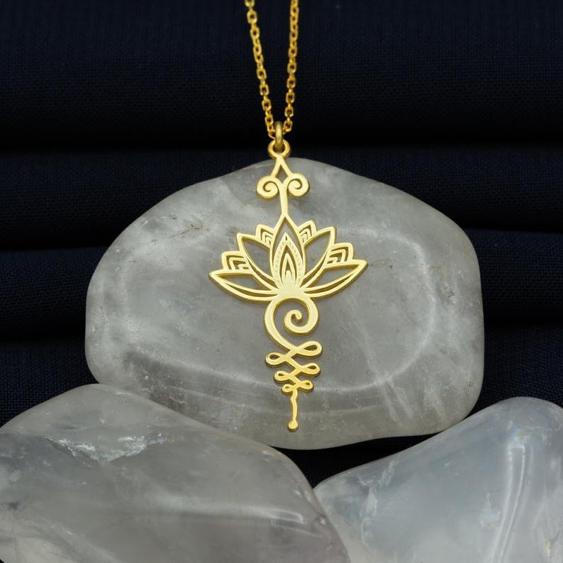 Goldene Lotusblume Halskette auf grauem Stein, eleganter Schmuck, Yoga inspiriert.
