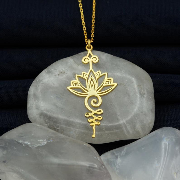 Goldene Lotusblume Halskette auf grauem Stein, eleganter Schmuck, Yoga inspiriert.