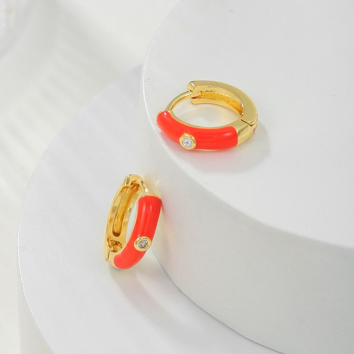 Goldene Creolen mit rotem Emaille und Zirkonia, modische Ohrringe, Schmuckaccessoire.