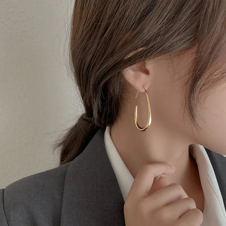 Frau mit goldenen Creolen-Ohrringen, elegantes Schmuckdesign, modisches Accessoire.