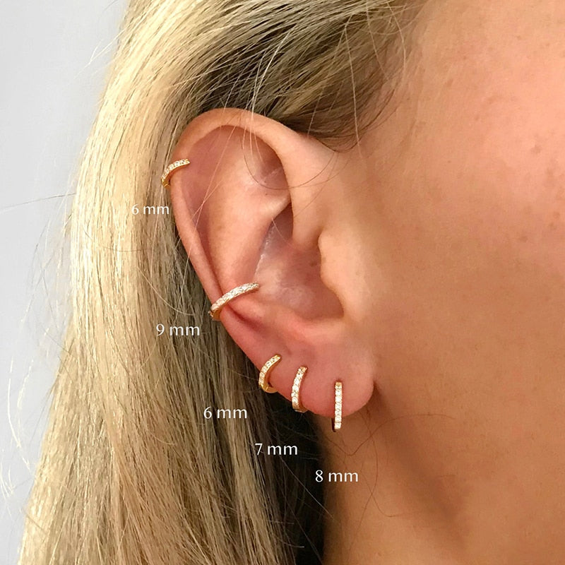 Frauenohr mit mehreren goldenen Ohrringen, Größenangaben, modischer Schmuck, Nahaufnahme.