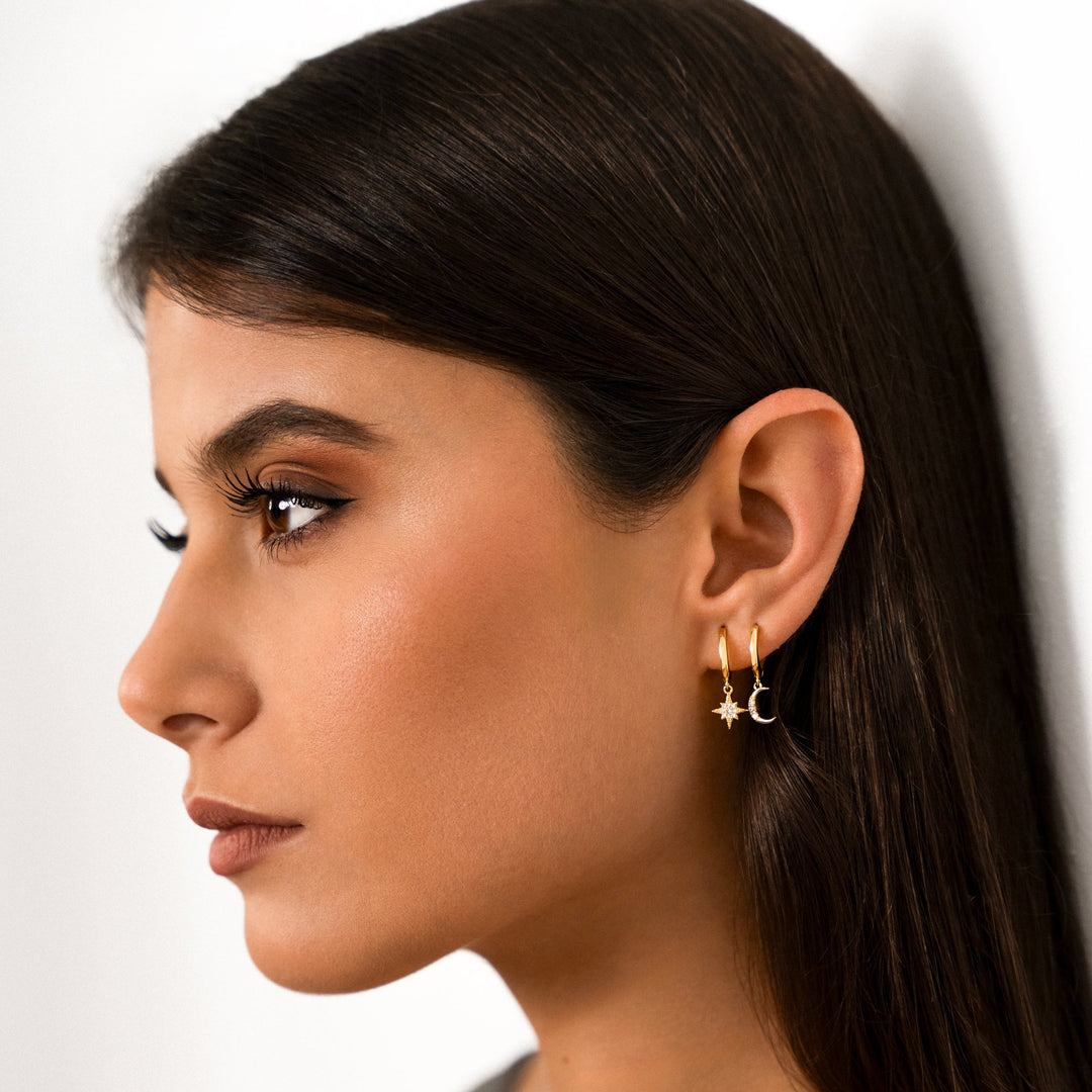 Frau mit goldenen Stern- und Mond-Ohrringen, Nahaufnahme, modischer Schmuck, seitliches Profil.