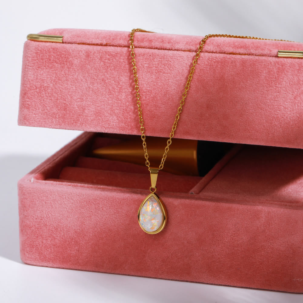 Goldene Halskette mit Opal-Anhänger auf rosa Schmuckbox, elegantes Schmuckdesign.