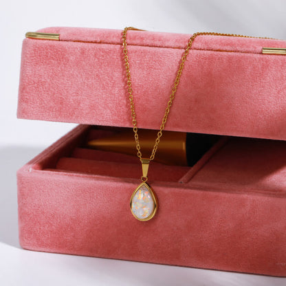 Goldene Halskette mit Opal-Anhänger auf rosa Schmuckbox, elegantes Schmuckdesign.