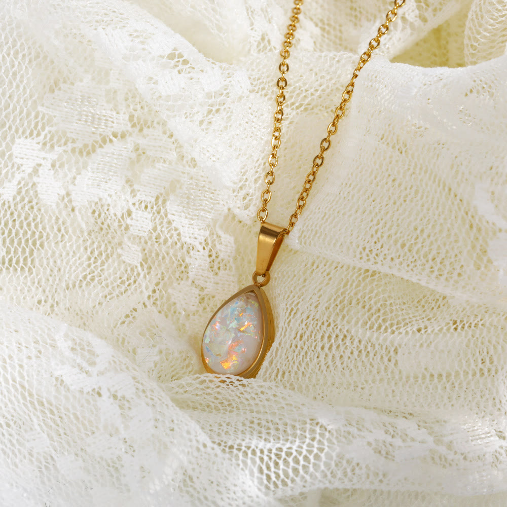 Goldene Halskette mit Opal-Anhänger auf weißer Spitze, eleganter Schmuck, Damenaccessoire.