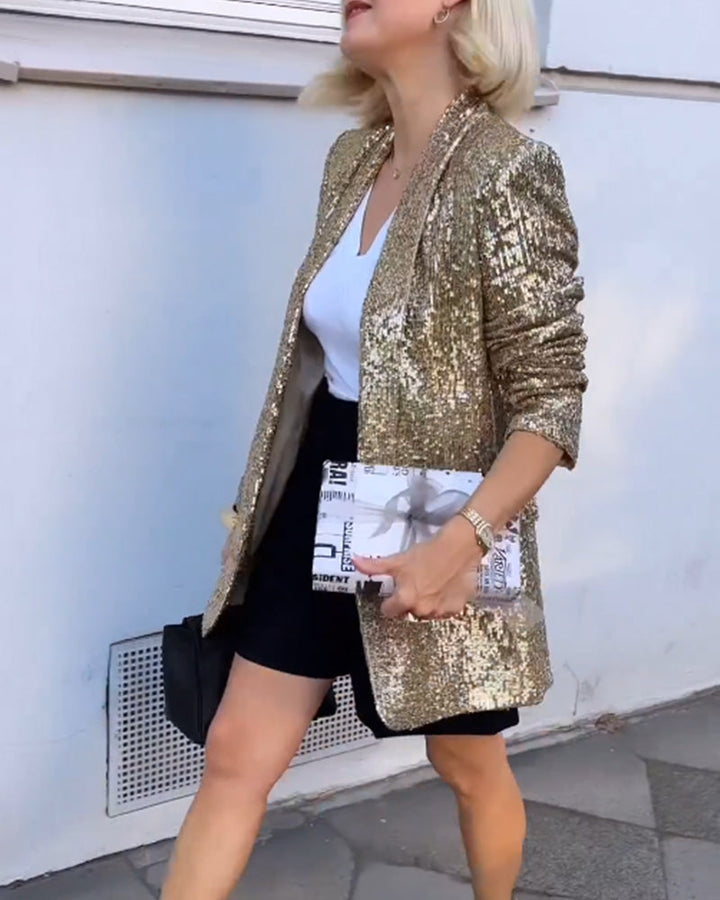 Frau in goldener Paillettenjacke, weißem T-Shirt, schwarzem Rock, hält Zeitungstasche.