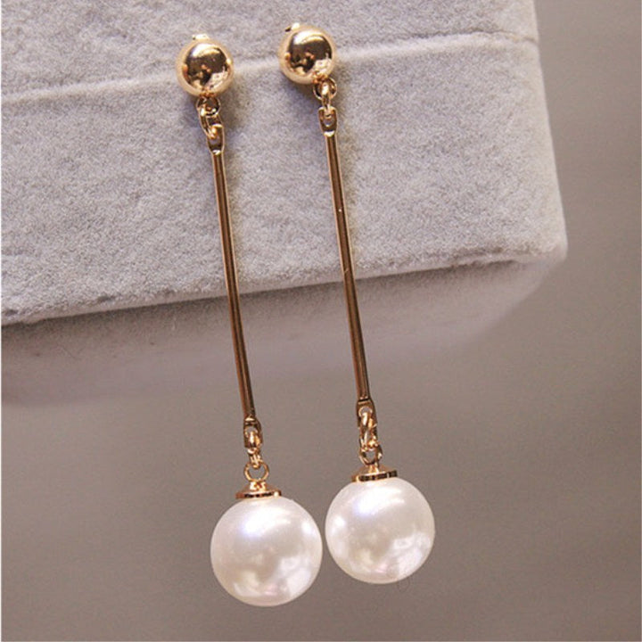 Goldene Ohrringe mit langen Stäben und weißen Perlen, eleganter Schmuck für Damen.