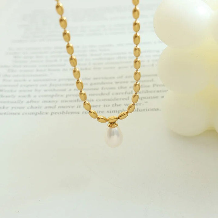 Goldene Halskette mit Perlenanhänger, eleganter Schmuck, Damenaccessoire, luxuriöses Design.