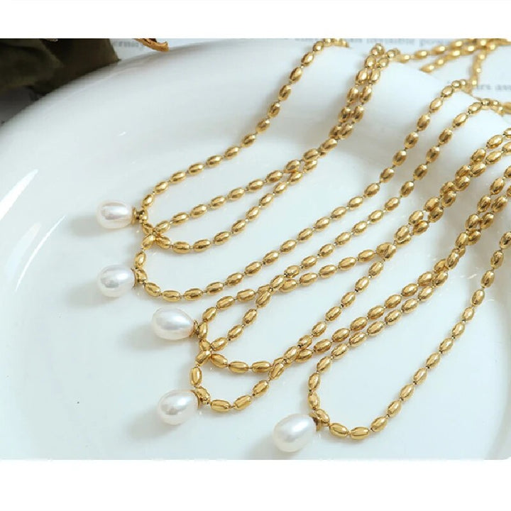 Goldene Halskette mit Perlenanhänger, eleganter Schmuck, Damenaccessoire, modisch, luxuriös.