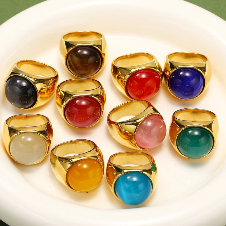 Zehn goldene Ringe mit bunten Edelsteinen auf weißem Teller, Schmuck, Accessoires, modisch.