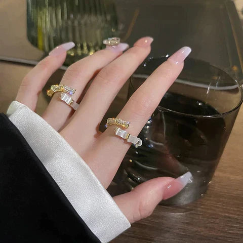 Elegante Damenhand mit goldenen Ringen und Glas, stilvolle Nagelkunst, modisches Accessoire.