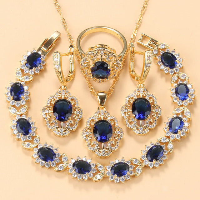 Goldene Schmuckset mit blauen Zirkonia, bestehend aus Armband, Ring, Ohrringen und Anhänger.