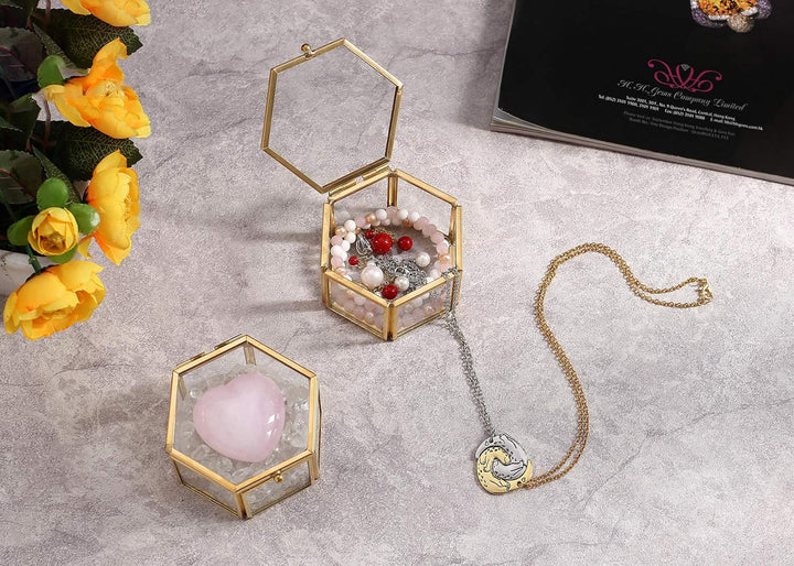 Goldene sechseckige Schmuckbox mit Perlen und Kette auf grauem Hintergrund, elegante Aufbewahrung.