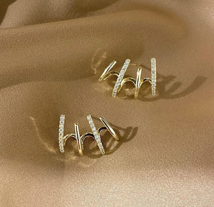 Goldene Ohrringe mit Diamanten auf Seide, eleganter Schmuck, luxuriöses Accessoire, Geschenkidee.