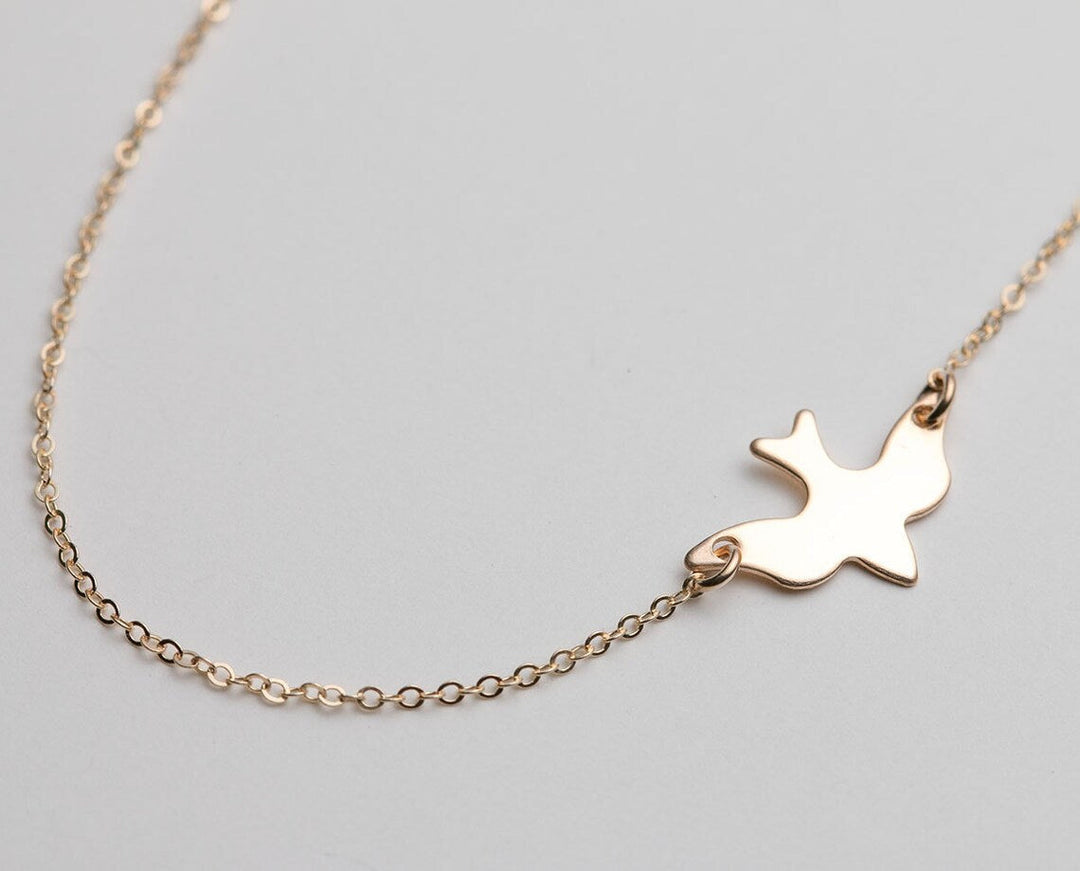 Goldene Halskette mit Taubenanhänger, filigranes Design, eleganter Schmuck für Damen.