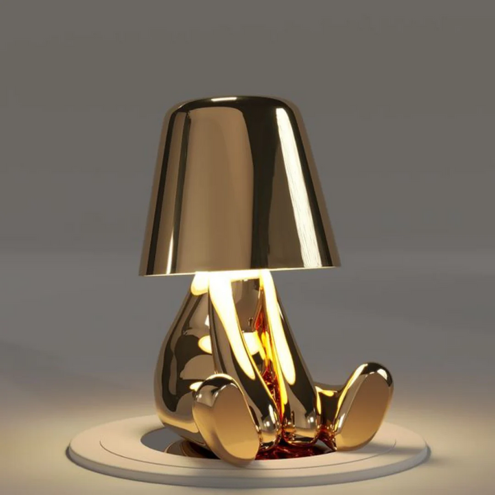 Goldene Tischlampe in Form einer sitzenden Figur, modernes Design, glänzend, dekorativ.