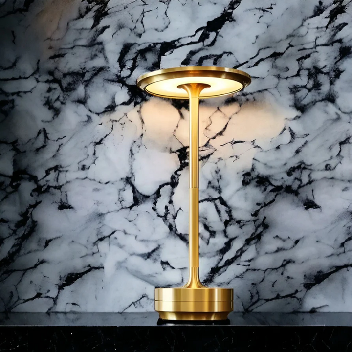 Goldene Tischlampe vor Marmortapete, modernes Design, elegante Beleuchtung, Inneneinrichtung.
