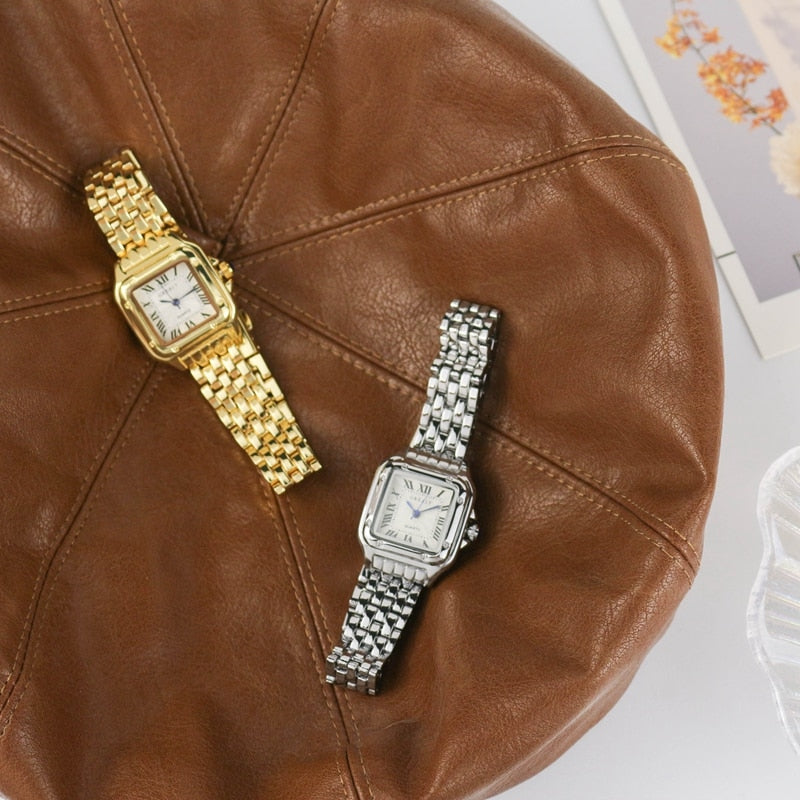 Zwei elegante Armbanduhren, gold und silber, auf braunem Lederhut, luxuriöses Design.