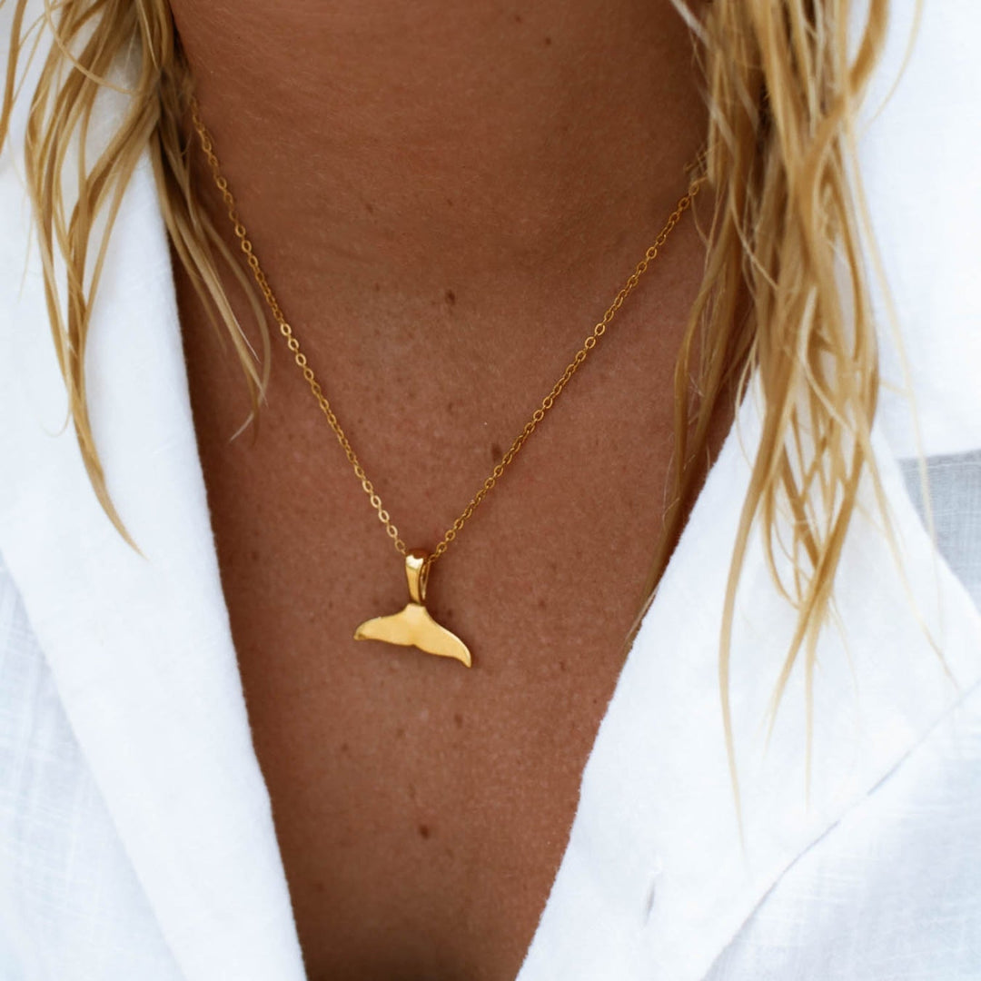 Goldene Walflossen-Halskette auf weißem Hemd, eleganter Schmuck für Damen.