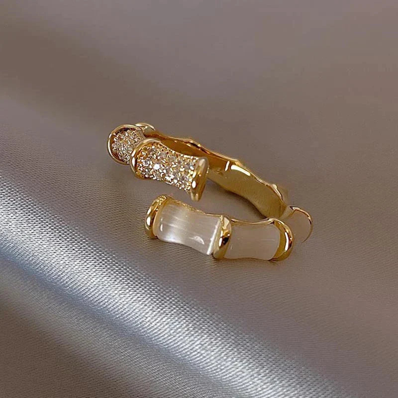 Goldener Ring mit Bambus-Design, verziert mit Kristallen, auf glänzendem Hintergrund.