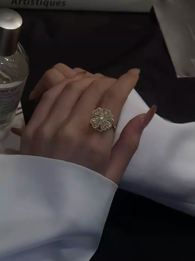 Damenhand mit goldfarbenem Blumenring, elegantes Schmuckdesign, stilvoller Modeschmuck.