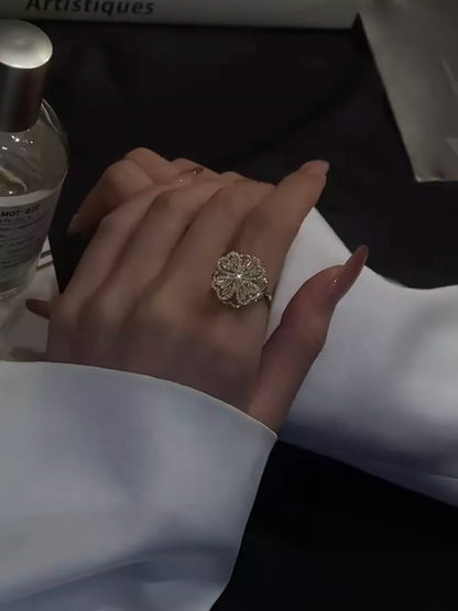 Damenhand mit goldfarbenem Blumenring, elegantes Schmuckdesign, stilvoller Modeschmuck.