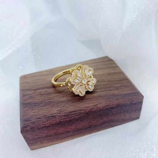 Goldener Blumenring auf Holzblock, eleganter Schmuck, Damenring, luxuriöses Design.