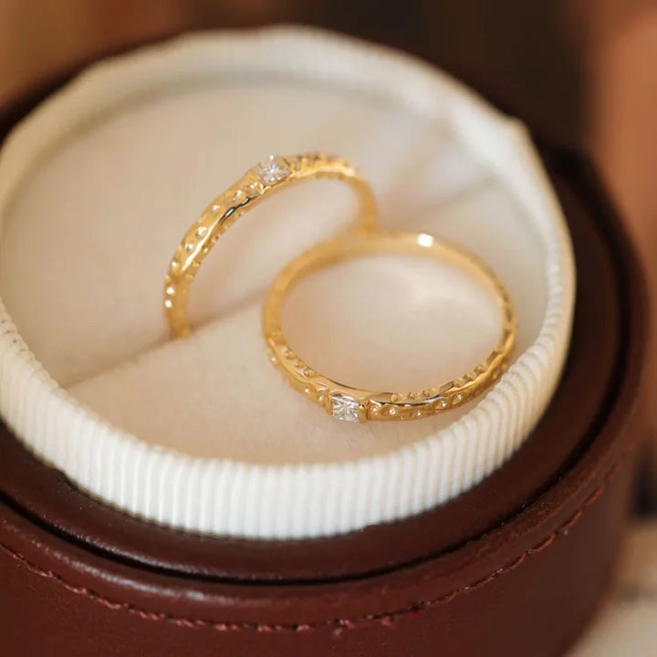 Zwei goldene Eheringe mit Diamanten in brauner Schmuckschatulle, elegant und hochwertig.