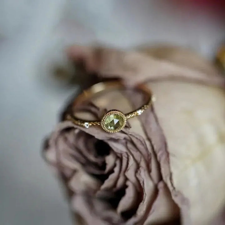 Goldener Verlobungsring mit Diamant auf getrockneter Rose, elegantes Schmuckdesign.