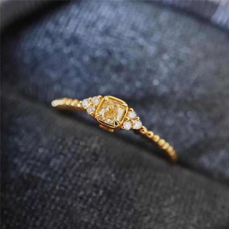 Goldener Verlobungsring mit gelbem Diamant und kleinen weißen Diamanten, elegantes Schmuckdesign.