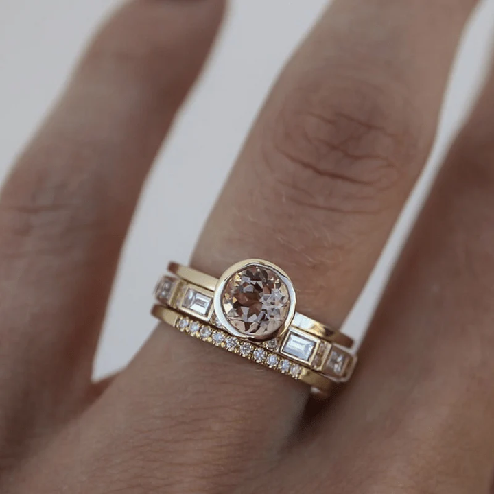 Goldener Verlobungsring mit ovalem Diamant und Ziersteinen auf Finger getragen.
