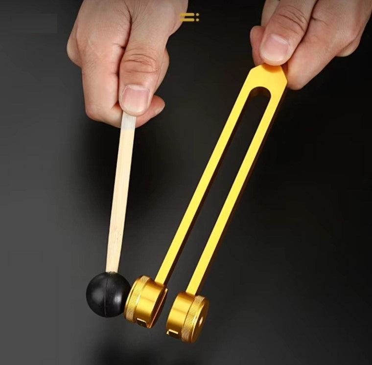Goldener Klangstab mit Schlägel, Musikinstrument zur Klangtherapie, Hand gehalten.