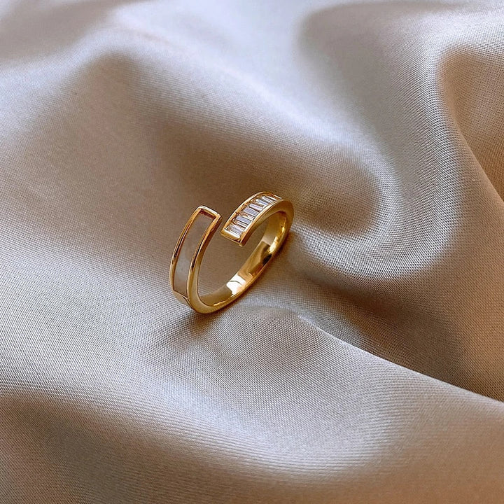 Goldener offener Ring auf beigem Satin, minimalistisches Design, eleganter Schmuck.