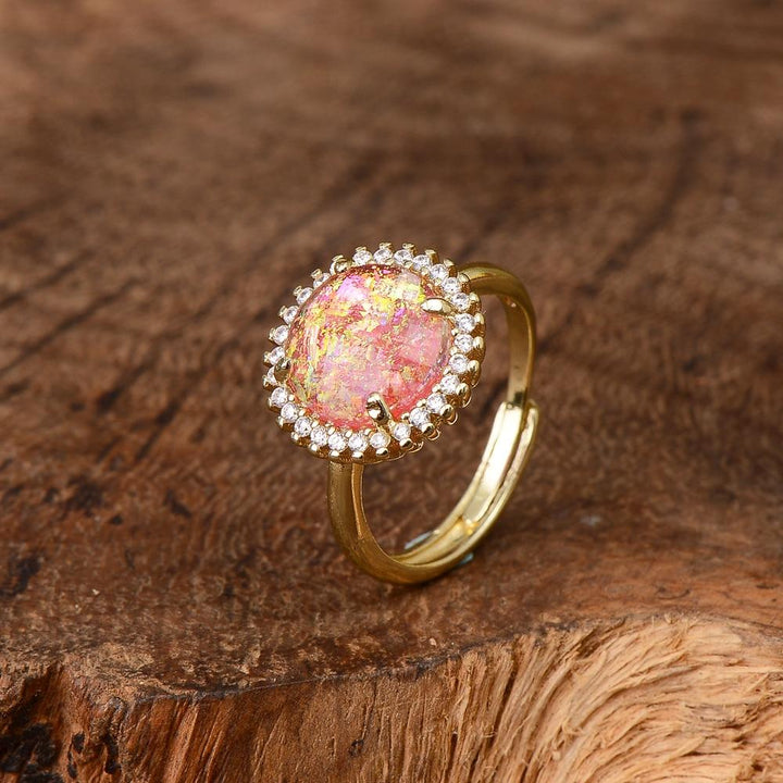 Goldener Ring mit rosa Opal und Zirkonia, verstellbar, auf Holzoberfläche.